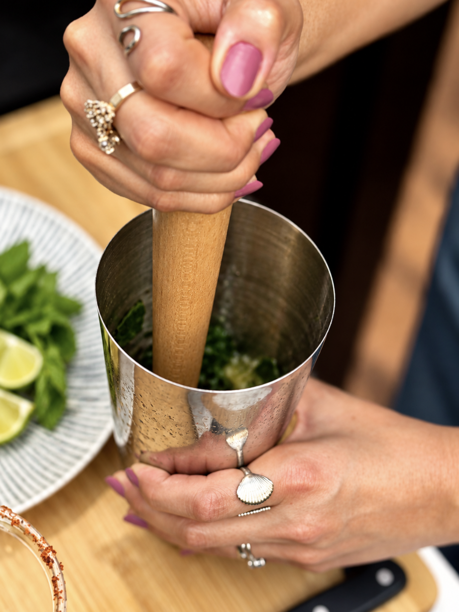 Bartender muddling fresh mint and lime for a cocktail